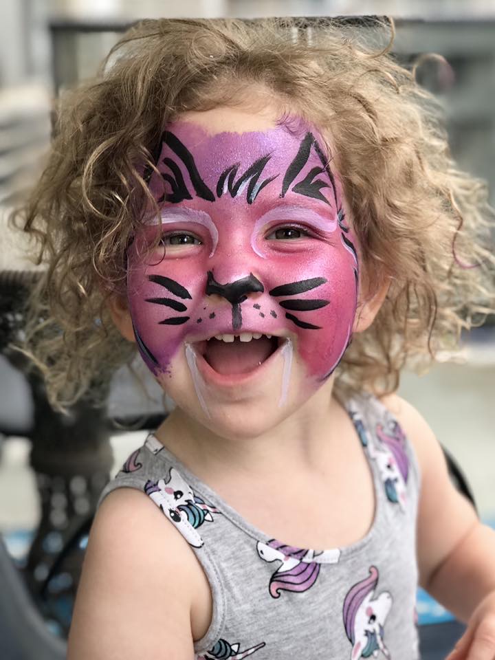 Smiling child with cute cat face painting in black and white