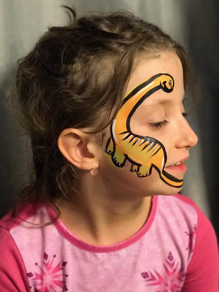 Excited child with green dinosaur face painting perfect for birthday parties