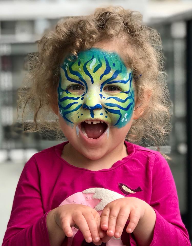 Child with detailed tiger face painting showing orange stripes and whiskers